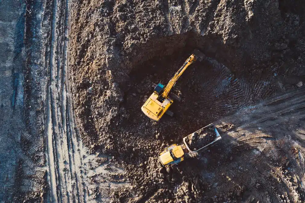 Aerial drone view of excavator loading the tipper truck at the construction site.