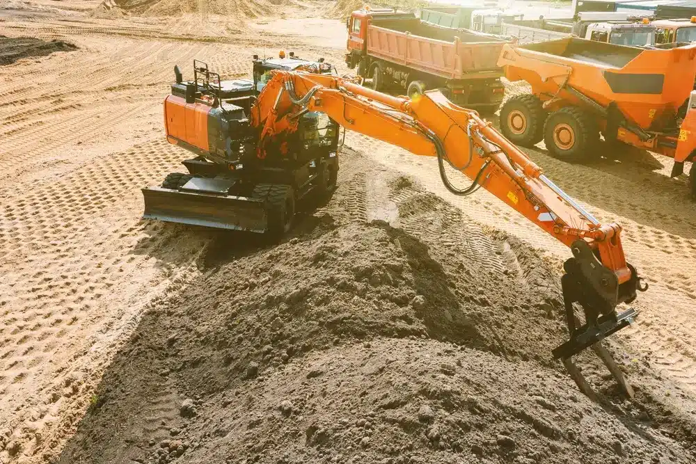 An excavator at a construction site plans the ground before work on the foundation.