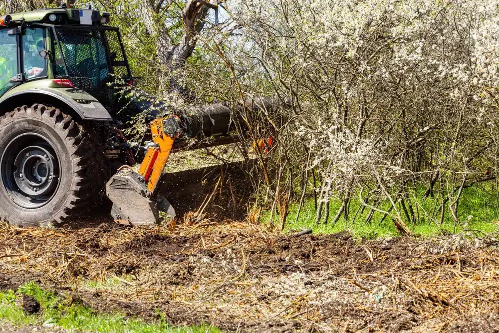 Attached to excavator forestry mulcher for clearing trees and brush along roadsides.