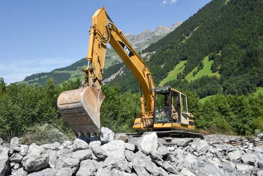 digger who rearranges a bed of a river after a landslide at Engelberg on the Swiss alps.